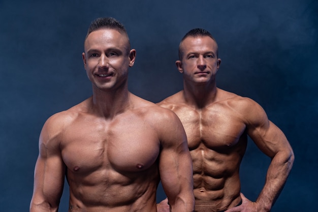 Two Muscular man isolated on the black surface