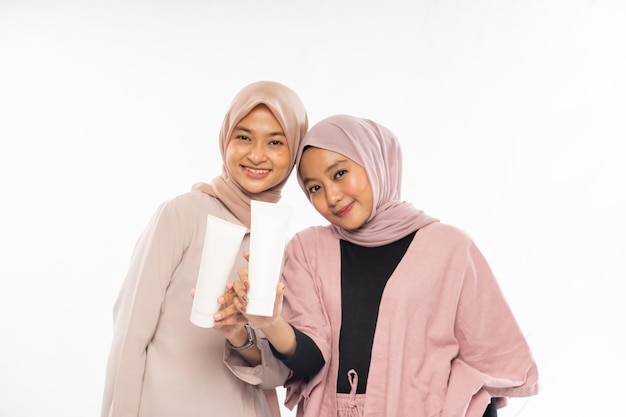 Two muslim beauty friend holding a tube cosmetic product for skincare