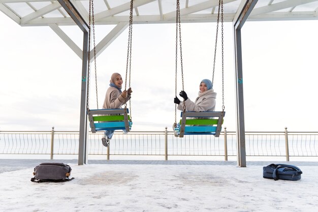 写真 ピアのそばを旅しながら揺れる2人のイスラム教徒の女性の友人