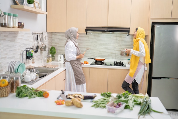Две мусульманские женщины веселятся, готовя вместе на кухне