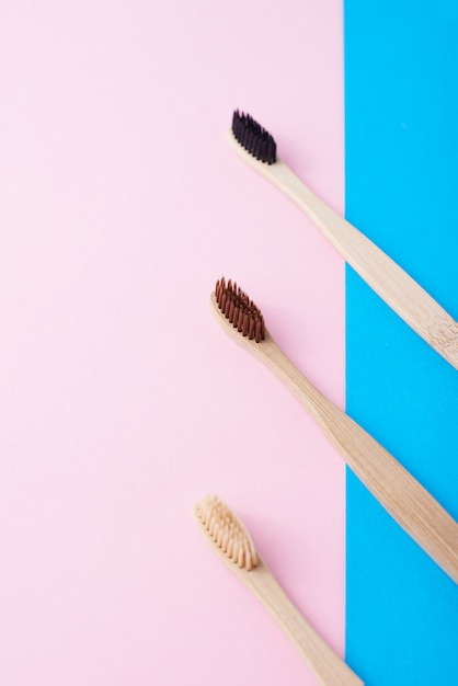 Two natural wooden toothbrushes on a blue and pink color background