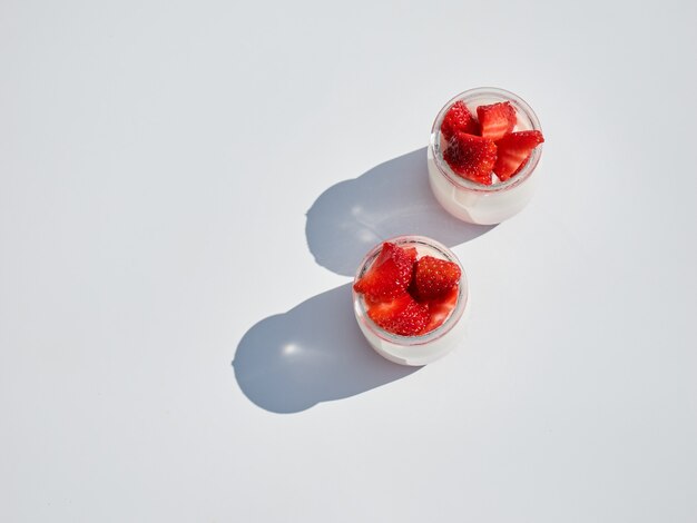 Two natural yogurts with fresh strawberries isolated on white