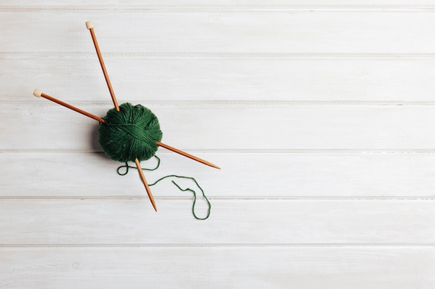 Two needles in green wool ball