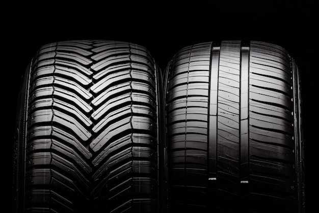 Two new summer and all-season tires close-up on a black wall.