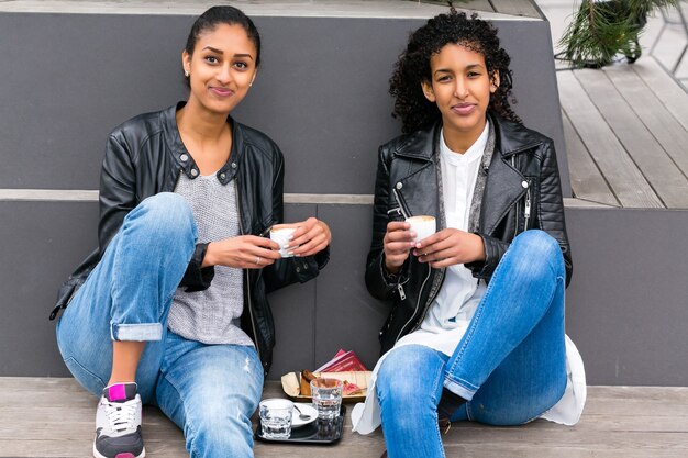 Two north African teen friends drinking together coffee outside