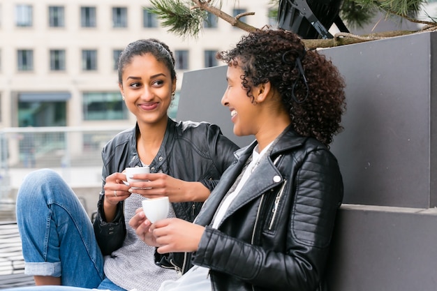 Two north African teen friends drinking together coffee outside