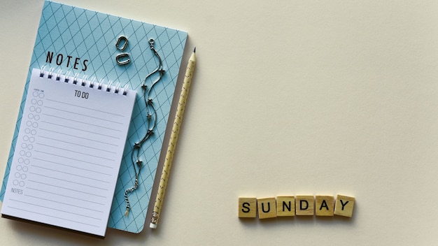 Two notepads with pencil and wooden word "Sunday"