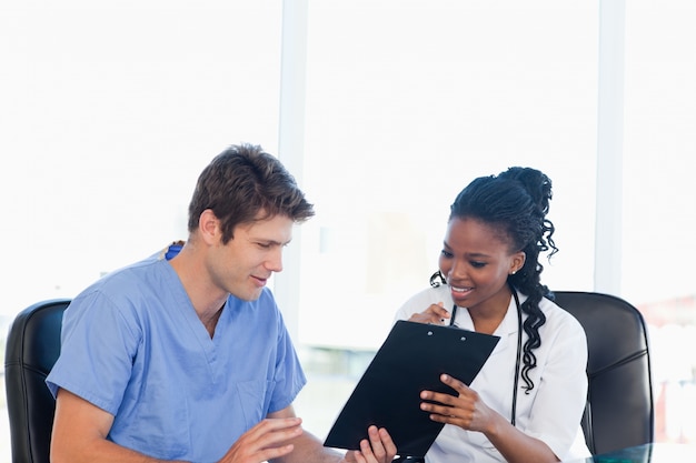 Photo two nurses working on a professional clipboard in a bright room