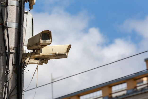 Two old cctv security surveillance cameras on street light pole on blue sky background