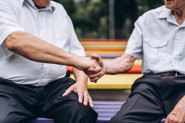 Two old senior adult men have a conversation outdoors in the city park.