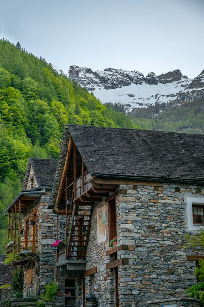 Two old stone houses standing in the valleyin the distance you can see mountains covered with snow