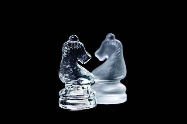 Two opponent glass chess knights on a black background copy space