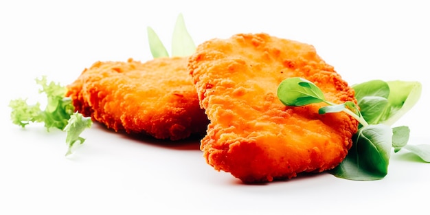 Two orange chicken nuggets with green leaves on a white background