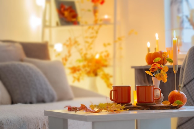 Two orange cups with hot drink in autumnal interior