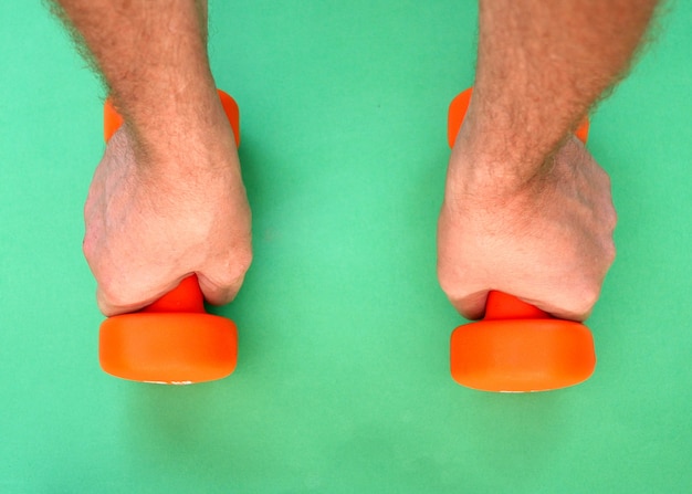 Two orange dumbbells lie on a green surface