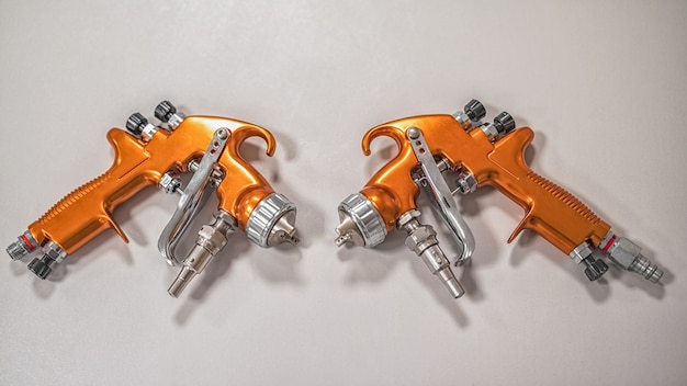 Two orange professional sprayers on a grey background.