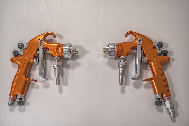 Two orange professional sprayers on a grey background.