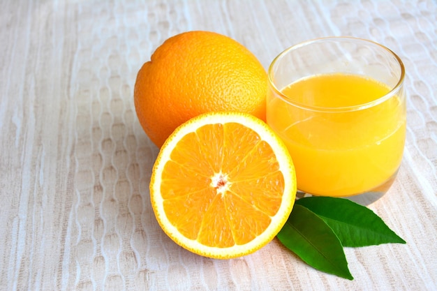 two oranges and a glass of orange juice on a table