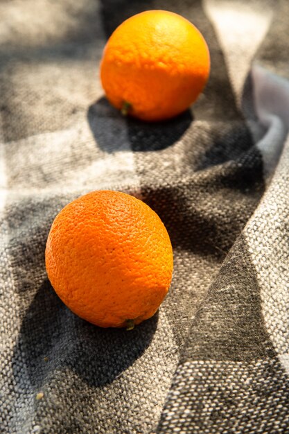 Photo two oranges on woolen plaidtwo oranges on grey black blanket  outdoor blanket for summer camping