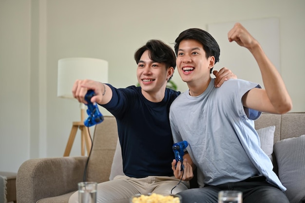Two overjoyed asian male friends celebrated their game wins while playing video games together