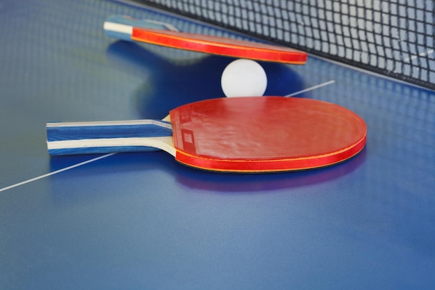 Two paddle tennis ball on blue ping pong table