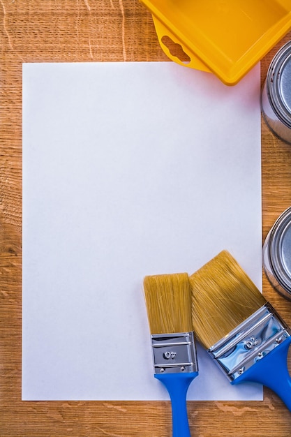 Foto vassoio di lattine di due pennelli su foglio di carta e tavola di legno