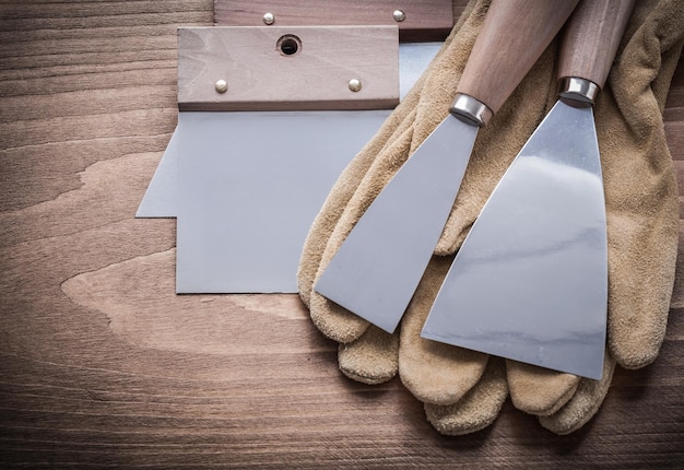 Two paint scrapers putty knifes working gloves