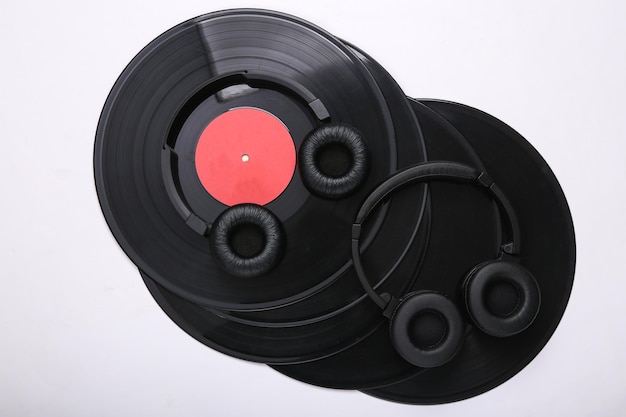 Photo two pairs of black stereo headphones and vinyl records on white background