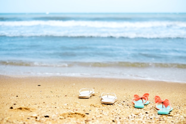 Two pairs of flip flops on the shore of the sea