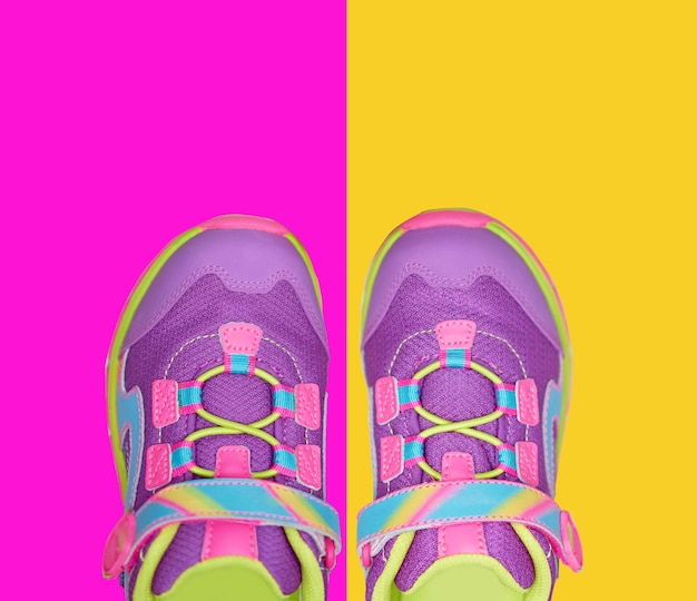 Two pairs of kid shoes on four pastel colors background