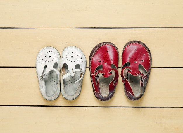 Photo two pairs of leather childrens sandals on yellow wooden