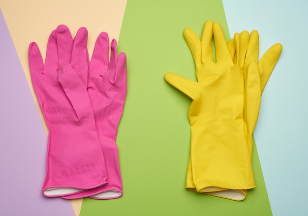 Two pairs of protective rubber gloves on a colored background