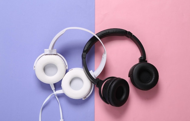 Two pairs of stereo headphones on pink purple background top\
view