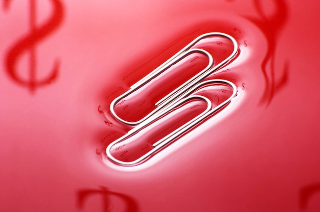 two paper clips on red background with dollar symbol