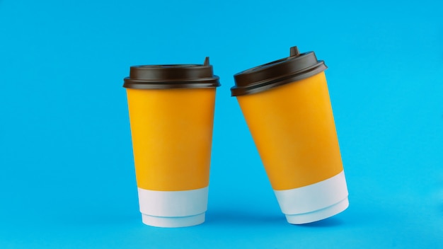 Фото Две бумажные кофейные чашки на синем фоне