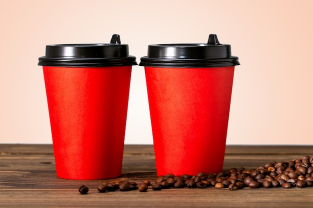 Two paper cup of coffee and coffee beans on wooden table.