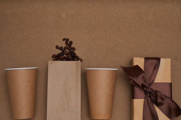 Two paper cups with coffee beans and a gift