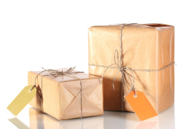 Two parcels wrapped in brown paper tied with twine and with blank labels isolated on white