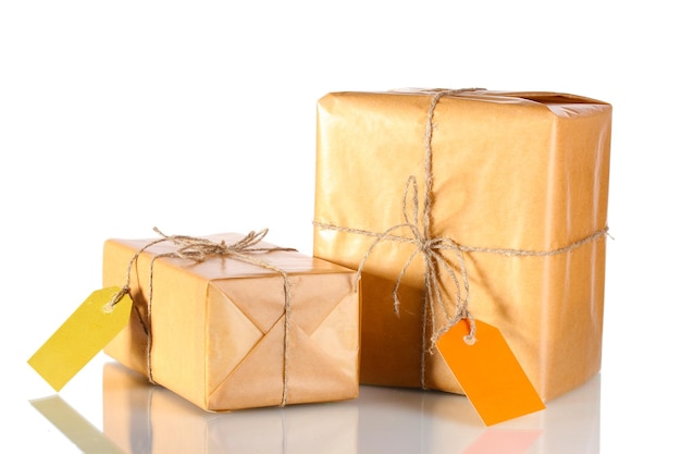 Two parcels wrapped in brown paper tied with twine and with blank labels isolated on white