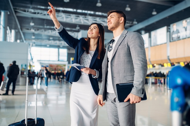 Two passengers of business class waiting in airport, working trip. Businessman and businesswoman in air terminal