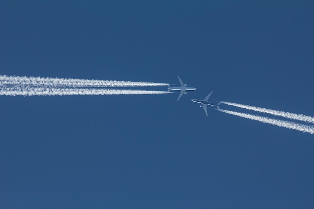 Two passengers jets are flying to each other in blue sky, telephoto shot