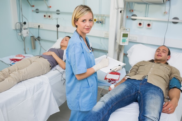 Two patients lying on bed next to a nurse