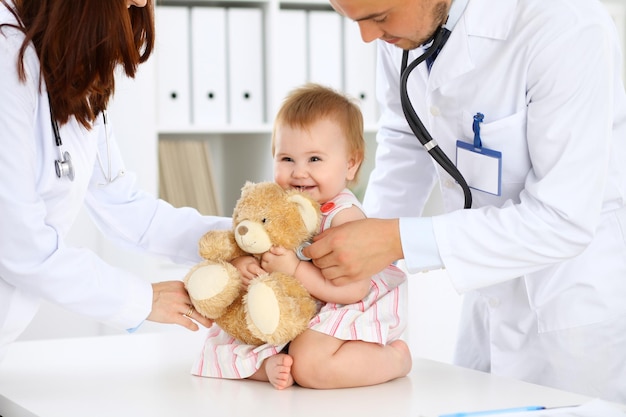 Two pediatricians are taking care of baby in hospital Little girl is being examining by doctor with stethoscope Health care insurance and help concept