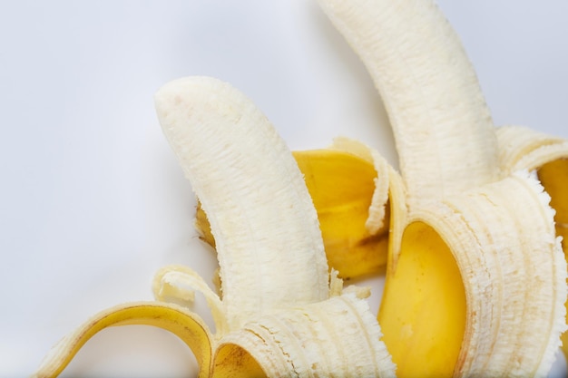 Два очищенных банана на сером фоне. Крупный план