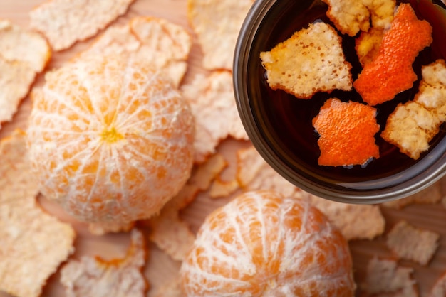 Two peeled tangerines near cup of hot tea with some added peel Adding tangerine peel to tea