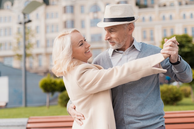 Two pensioners dance on the square near the bench