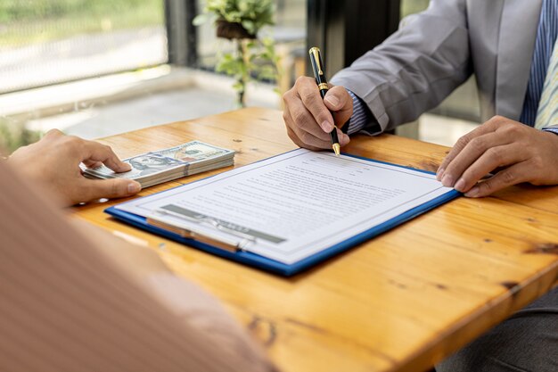 Photo two people are doing corrupt behavior, they are mutual business partners and are signing contracts to receive bribes for mutual benefit. the concept of business fraud and bribery is illegal.