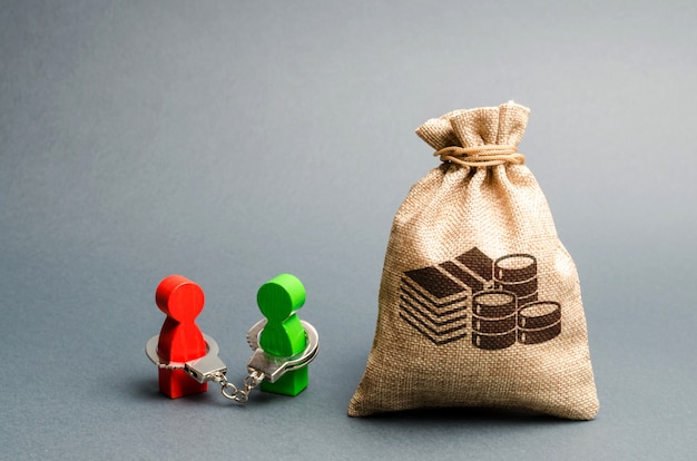 Photo two people are handcuffed to each other and stand near a money bag