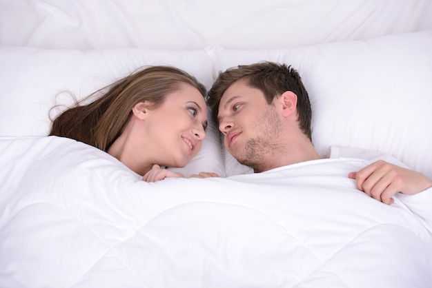 Two people are lying in bed and relaxing.