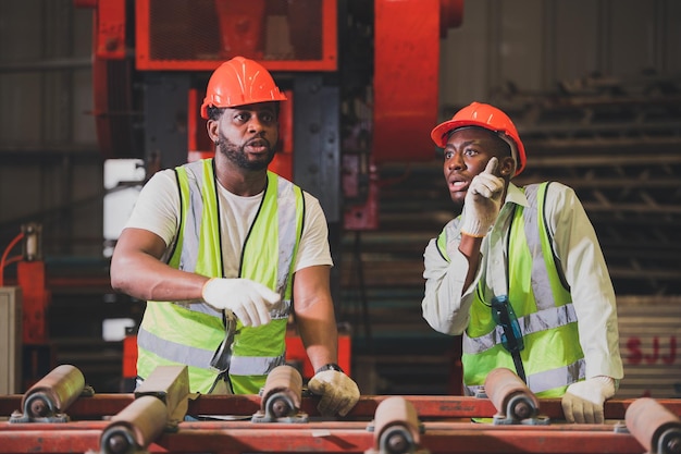 Two people black man African American worker control heavy machine in the factory